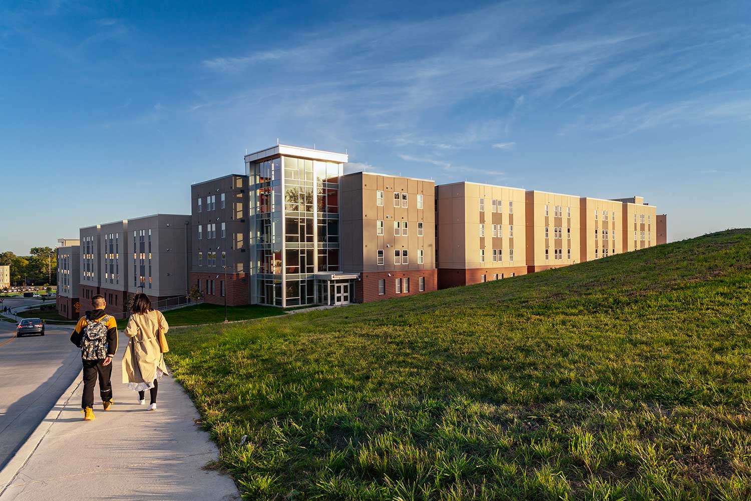 Two students walking down the sidewalk toward Stouffer Place Apartments. 