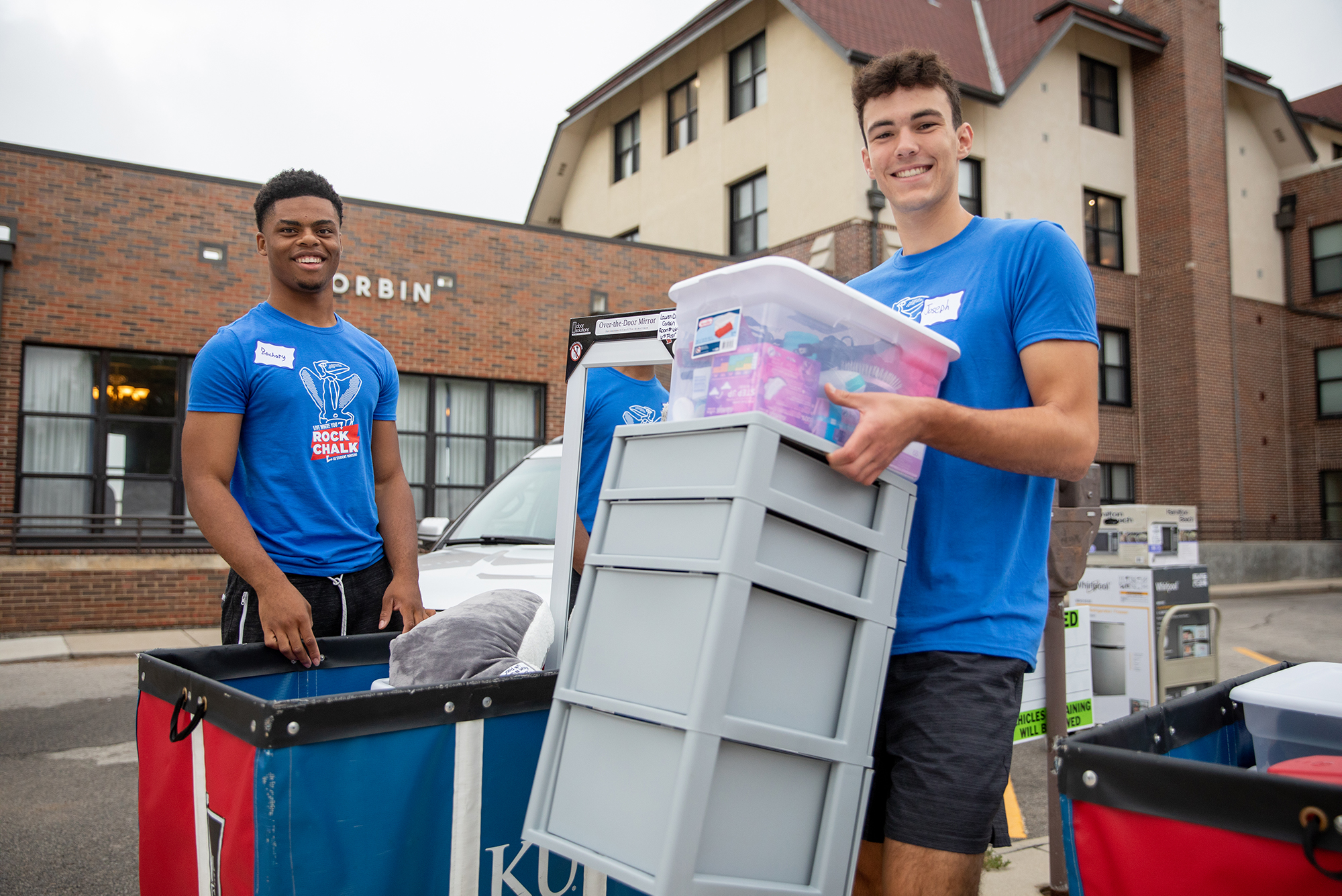 a pair of smiling students helping carry boxes on move-in day