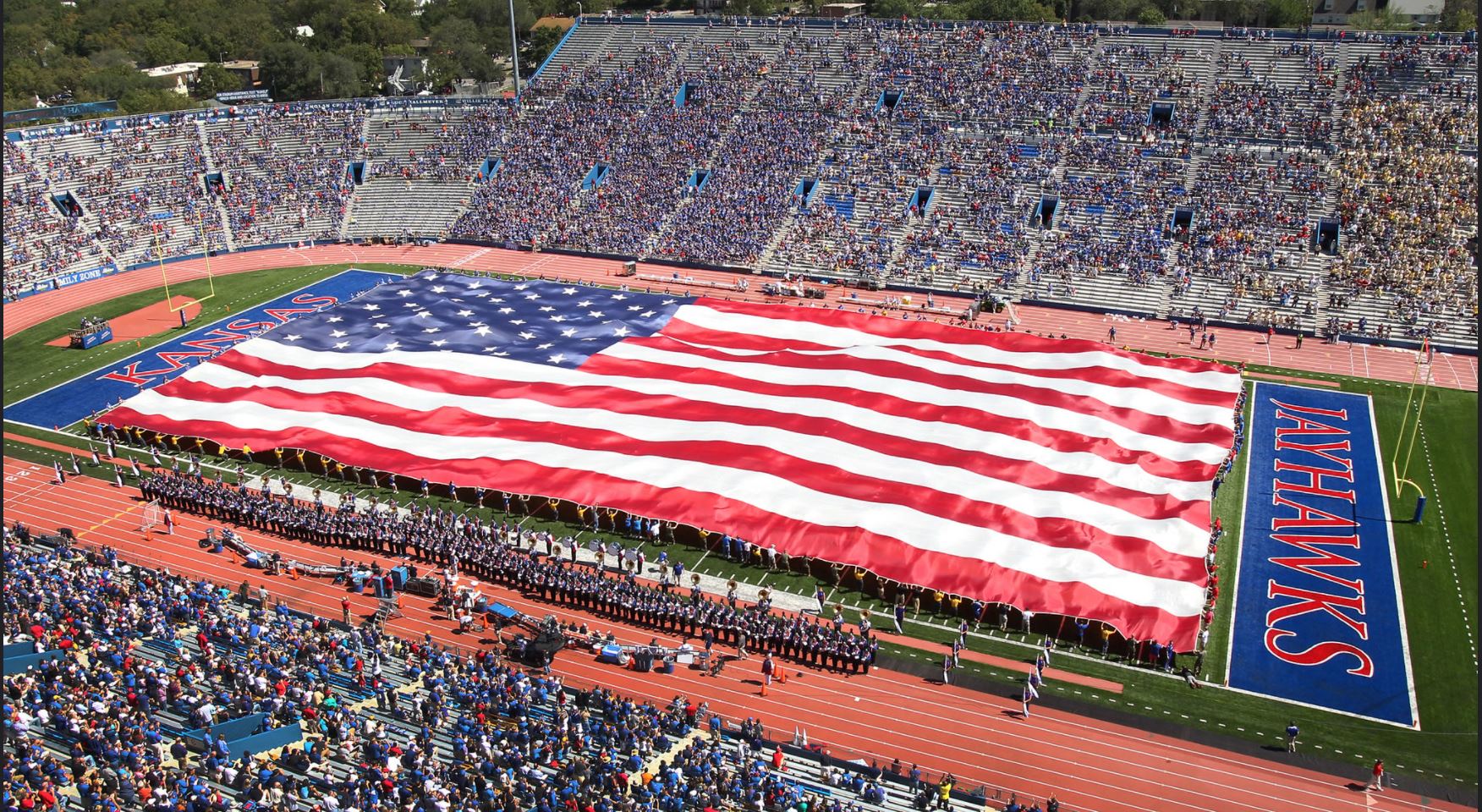 ROTC students unfurling a massive American flag over the football field in Memorial Stadium