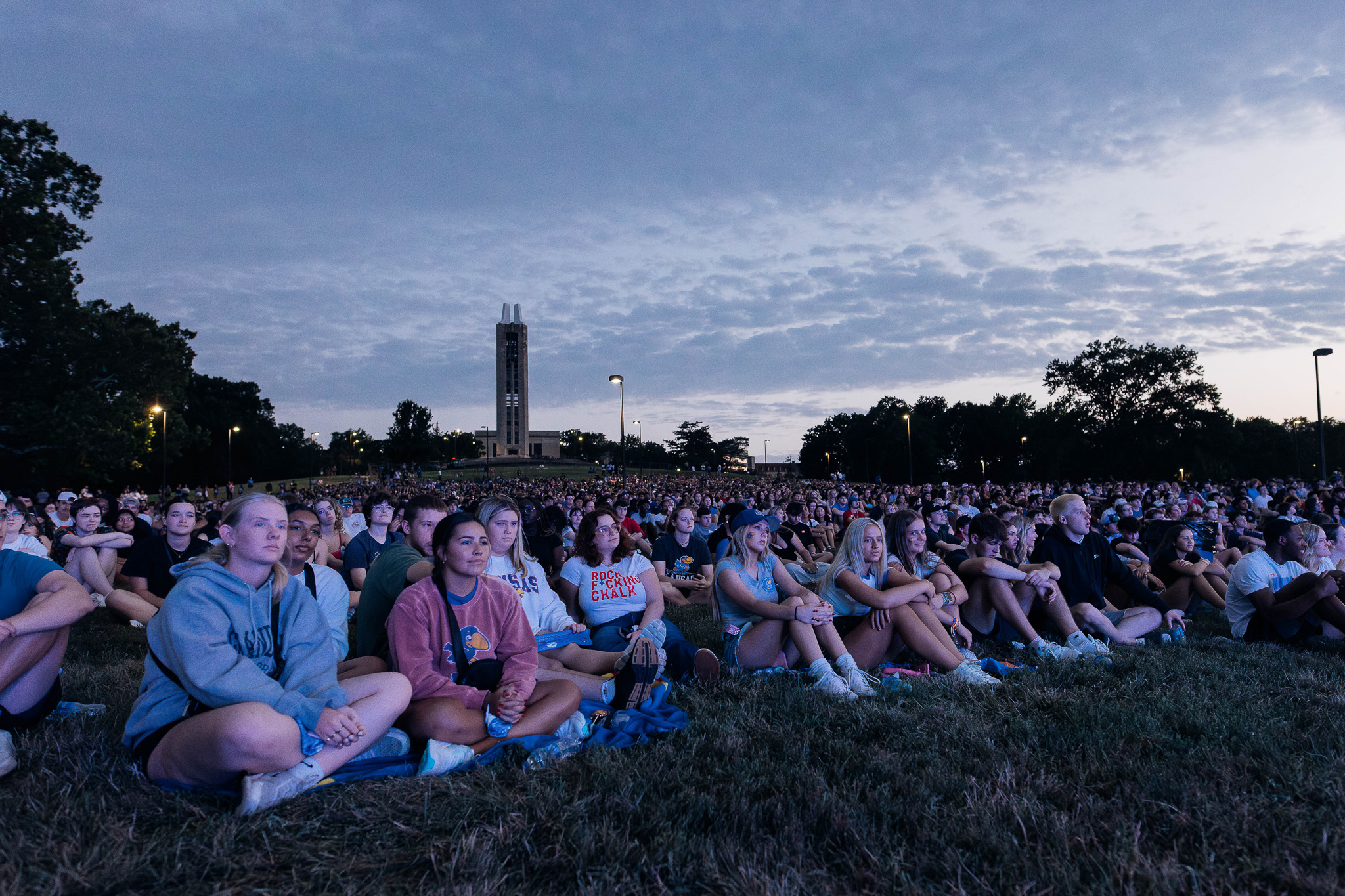 Large group of students sitting on the hill in front of Campanile