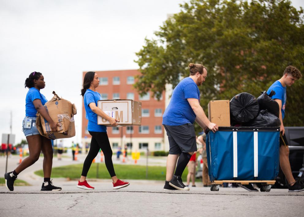 a line of student volunteers helping carry and cart boxes on move-in day