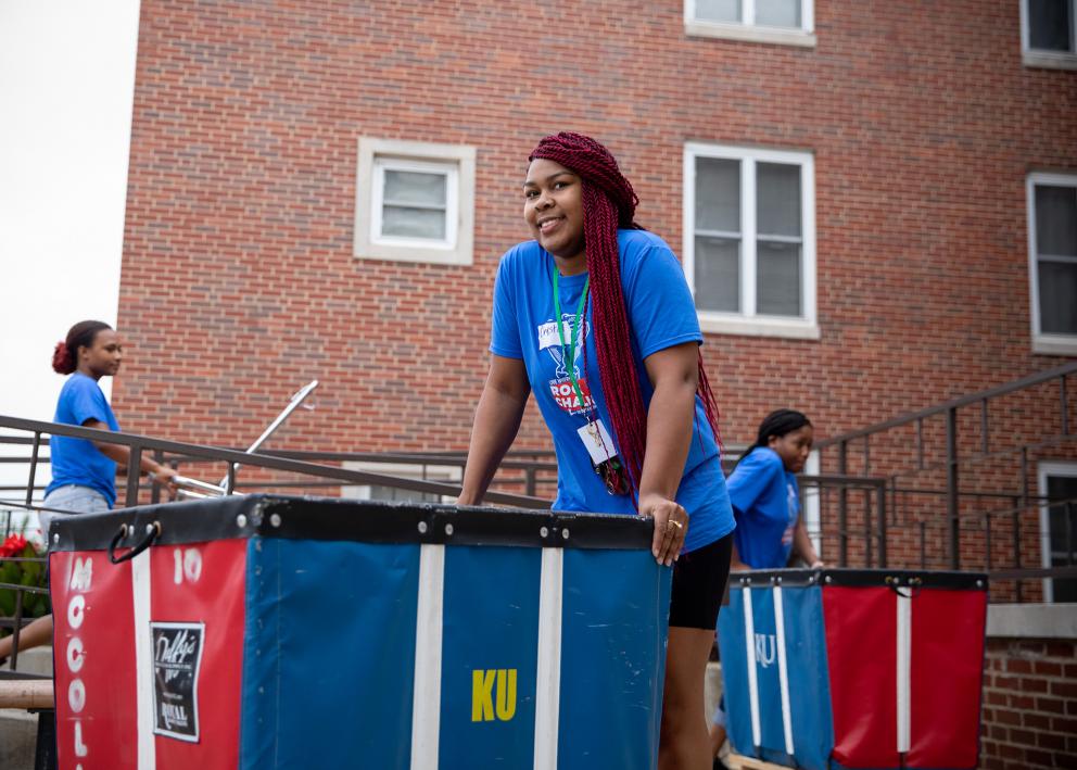 a smiling student volunteer pushing a cart on move-in day