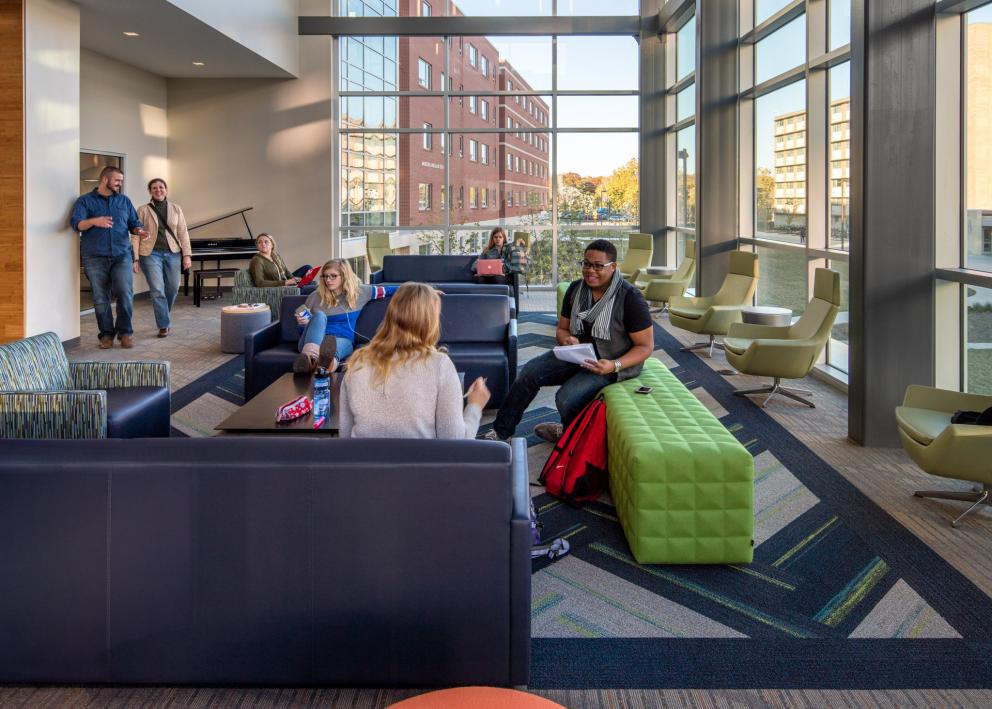 groups of students conversing and studying in the bright and airy Daisy Hill Commons living room
