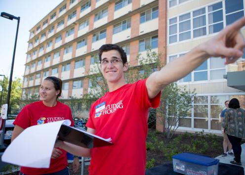 a smiling student employee helping give directions on move-in day