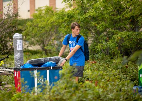 a student pulling a loaded cart up to his residence hall on move-in day