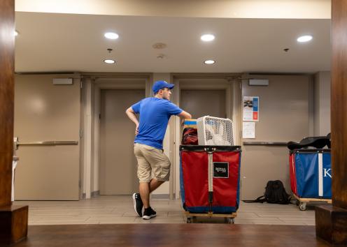 a student volunteer pausing to rest while waiting with his cart for the elevator on move-in day