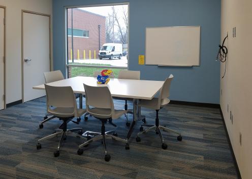 a small meeting room with table, chairs, and whiteboard