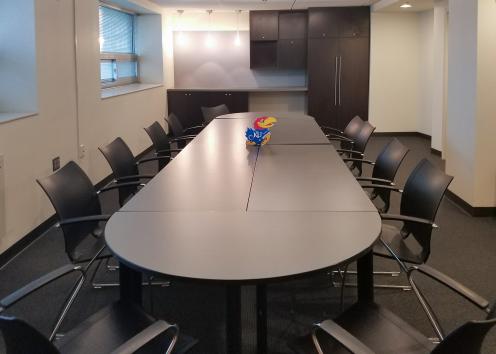 long conference room with table, chairs, and countertop space with cabinets