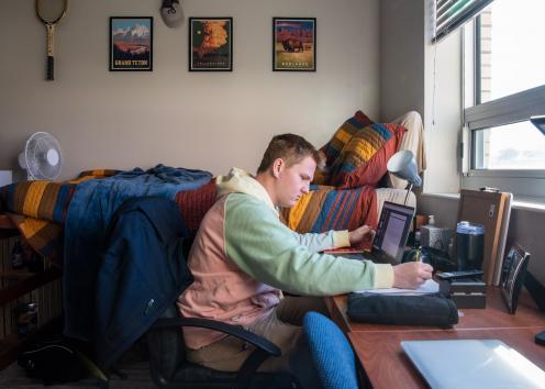 a student studying at their desk in their room in Oswald Hall